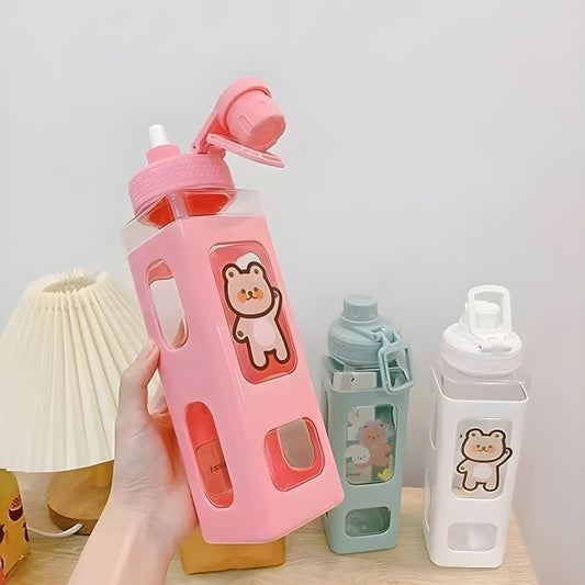 Pink water bottle with bear design held by a hand, with two other bottles in the background.