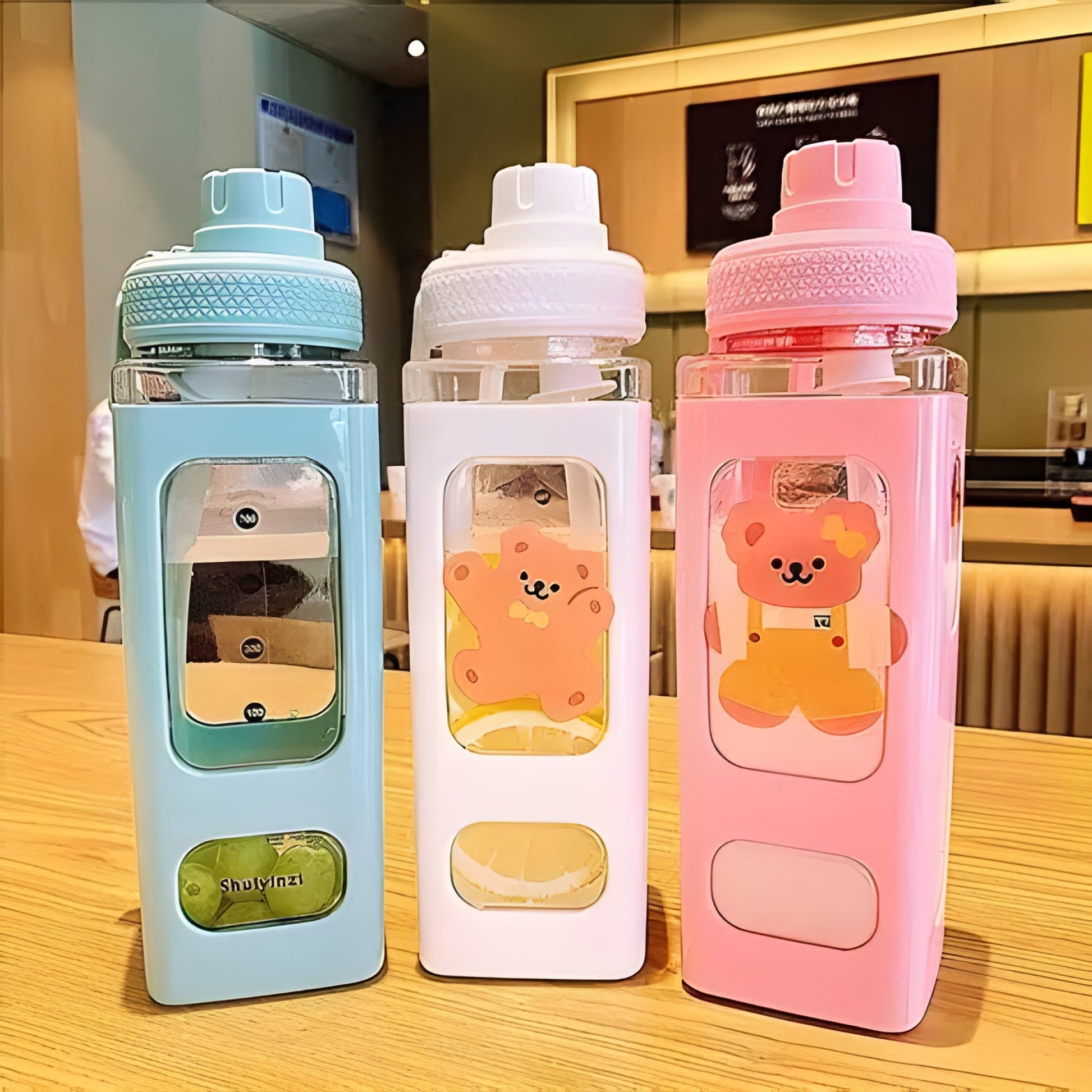 Three colorful water bottles with bear designs on a wooden table.